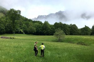 2 Hommes se promenant dans une prairie au pieds des montagnes